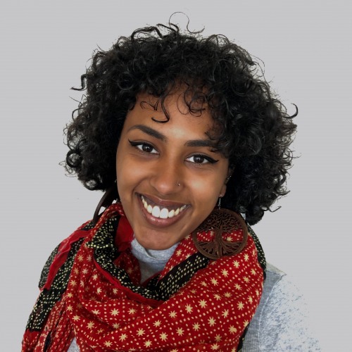 An image of Senit Kidane smiling with a bright red scarf.