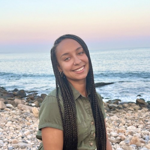 Kiana Knight on a beach at sunset, smiling and looking into the camera