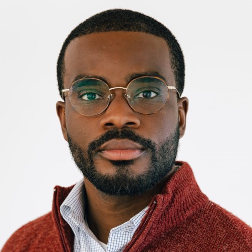 Eric Jones wearing glasses and a red sweater and looking into the camera