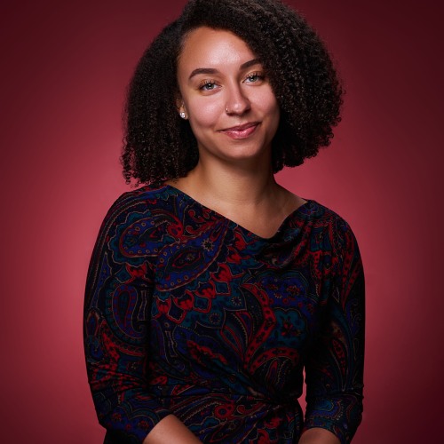 Kiana Knight with red background smiling at camera