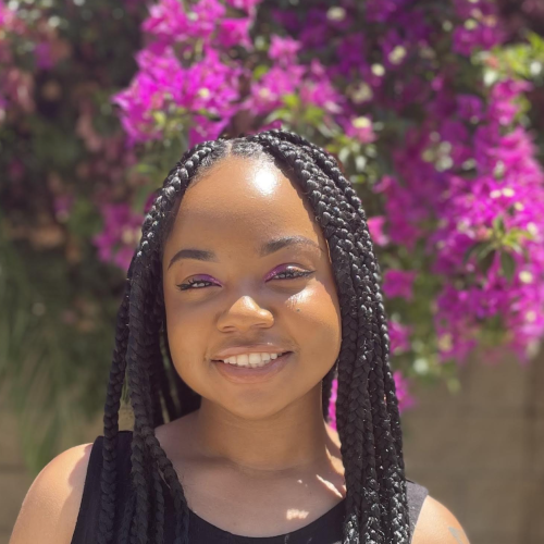 Camille in front of purple flowers smiling at the camera