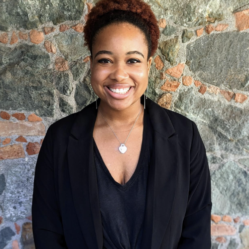 Lauren Prince in front of a stone wall smiling at the camera