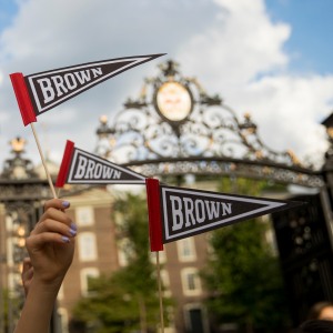 An image of students waving Brown pennants over Van Wickle Gates.